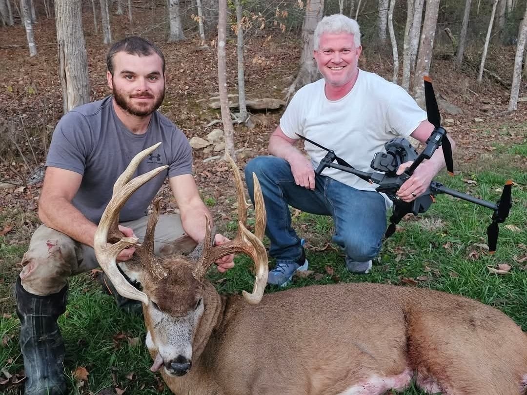 A hunter and a drone pilot with a recovered whitetail buck